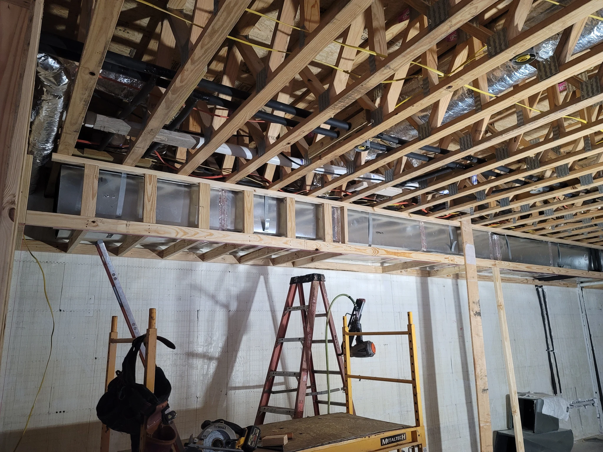 Open-web floor trusses with ductwork running through them between the chords.