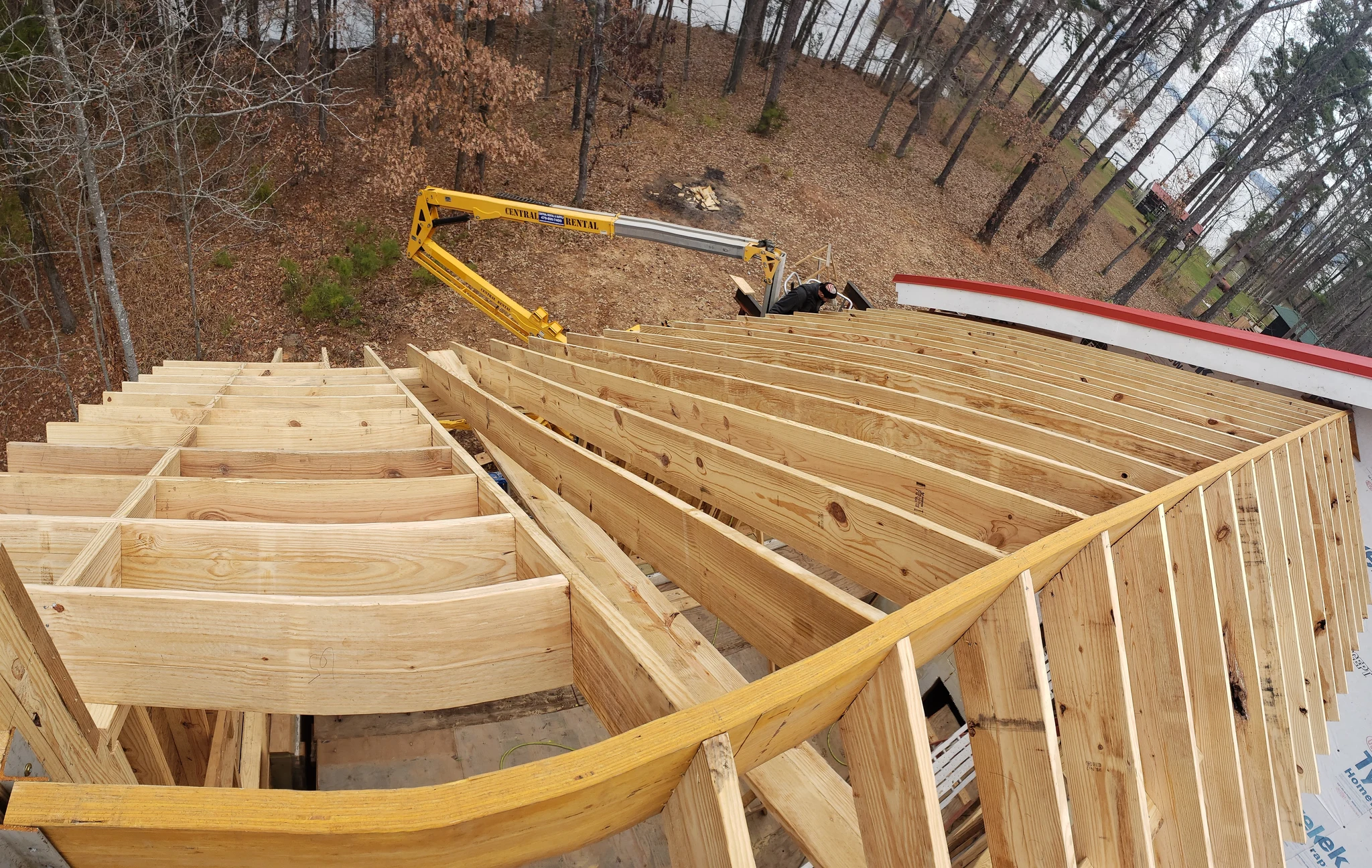 Curved roof framing members being lifted into place by a boom.