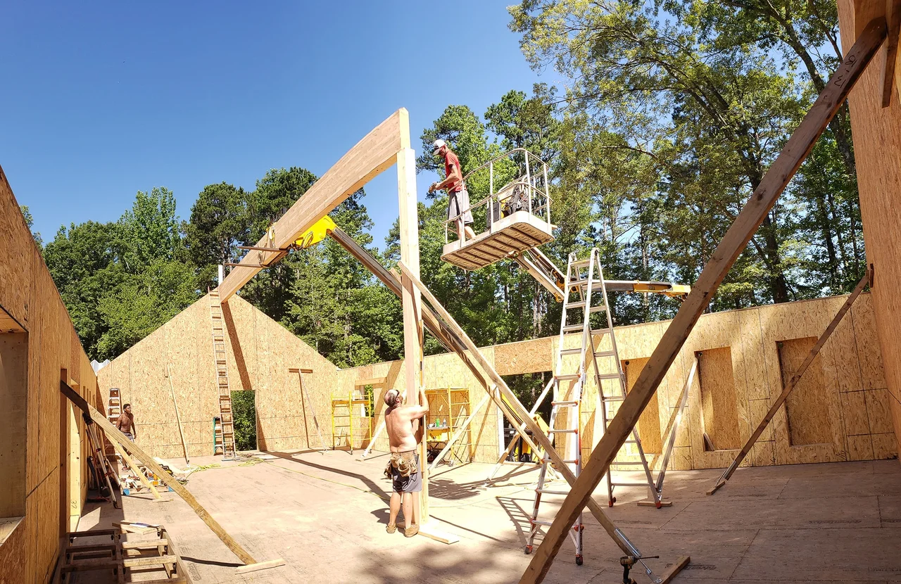 A framing crew raising a gable wall section into place.