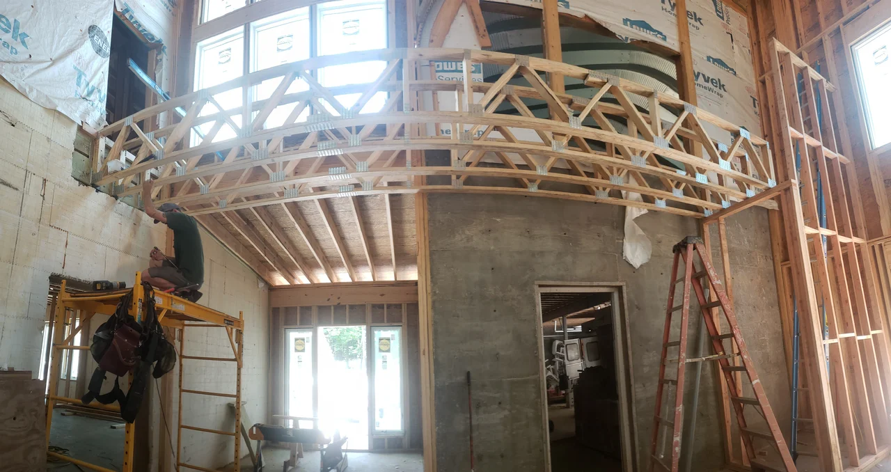Interior view of a curved framed truss spanning a wide opening.