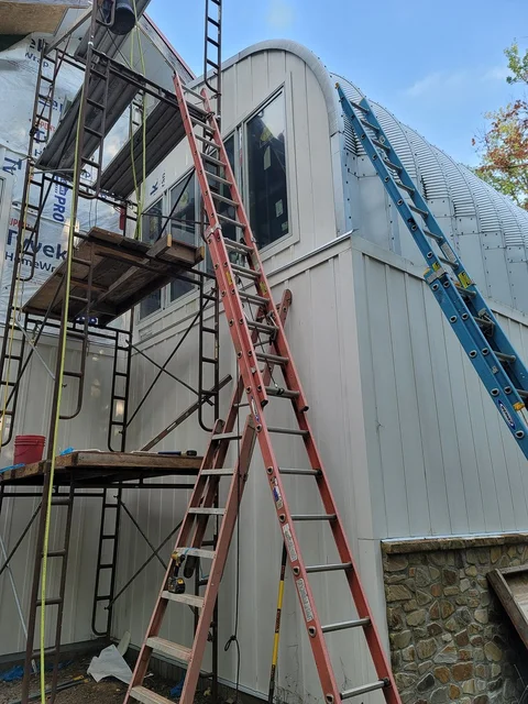 Ladders against the arch building as the end wall is clad.