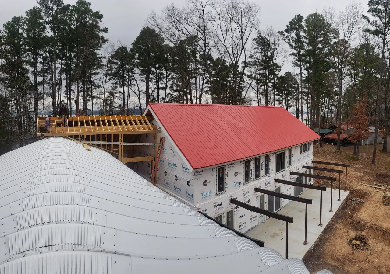 Aerial view of the steel arch meeting the red gable roof.