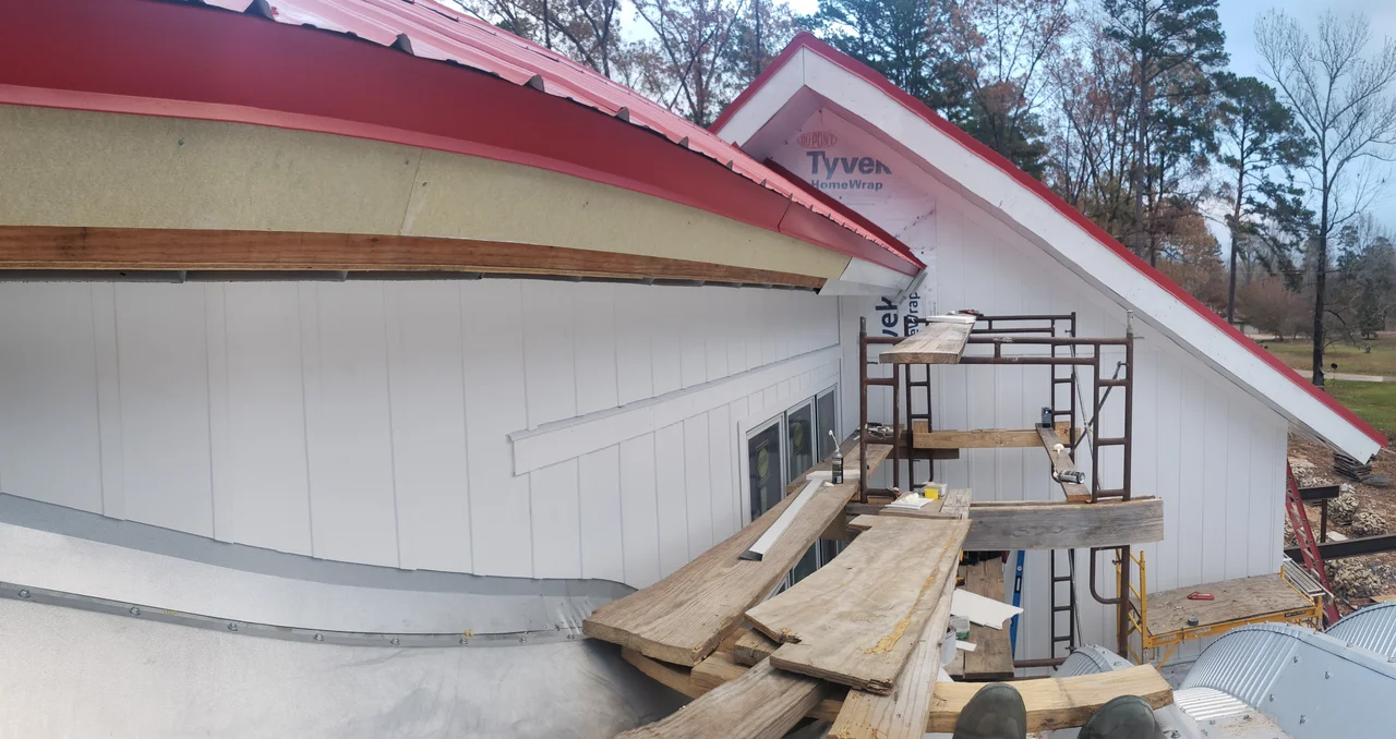 Close view of the arch curve running into the red standing-seam roof.