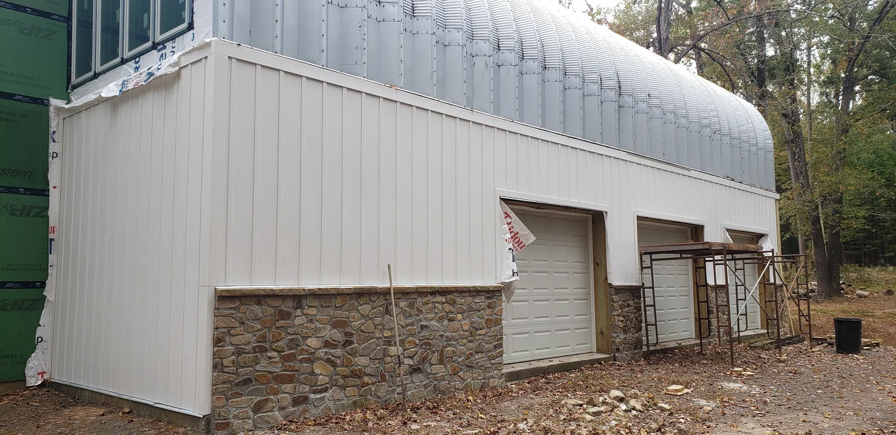 The clad end of the arch building with a garage door set in.