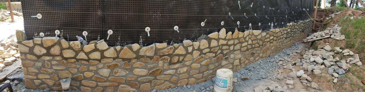 Wide view of the stone base course with drainage board behind it.