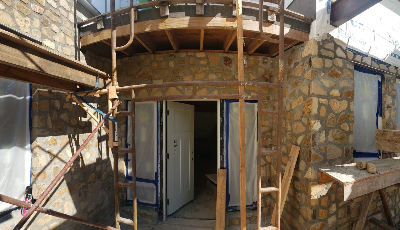 The curved stone wall meeting the timber framing above.