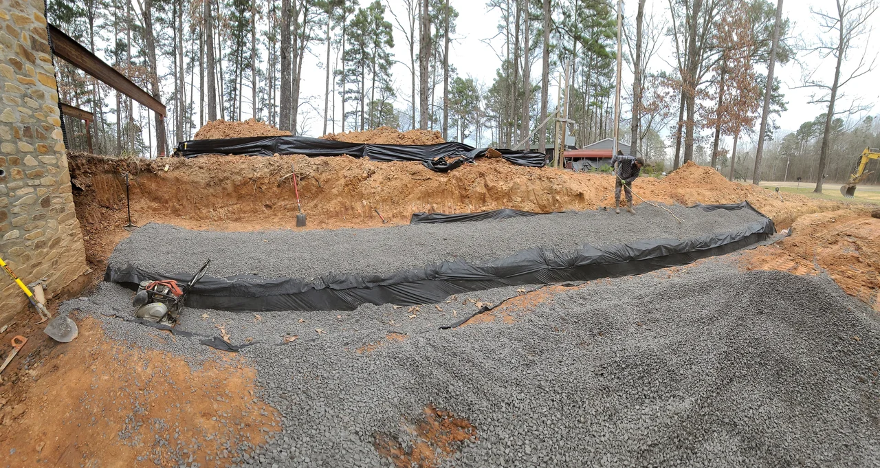 A drainage run bedded in gravel over geotextile fabric.