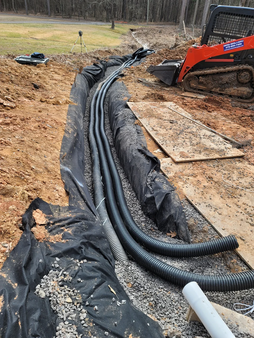 Bundled conduit runs laid over fabric before backfill.
