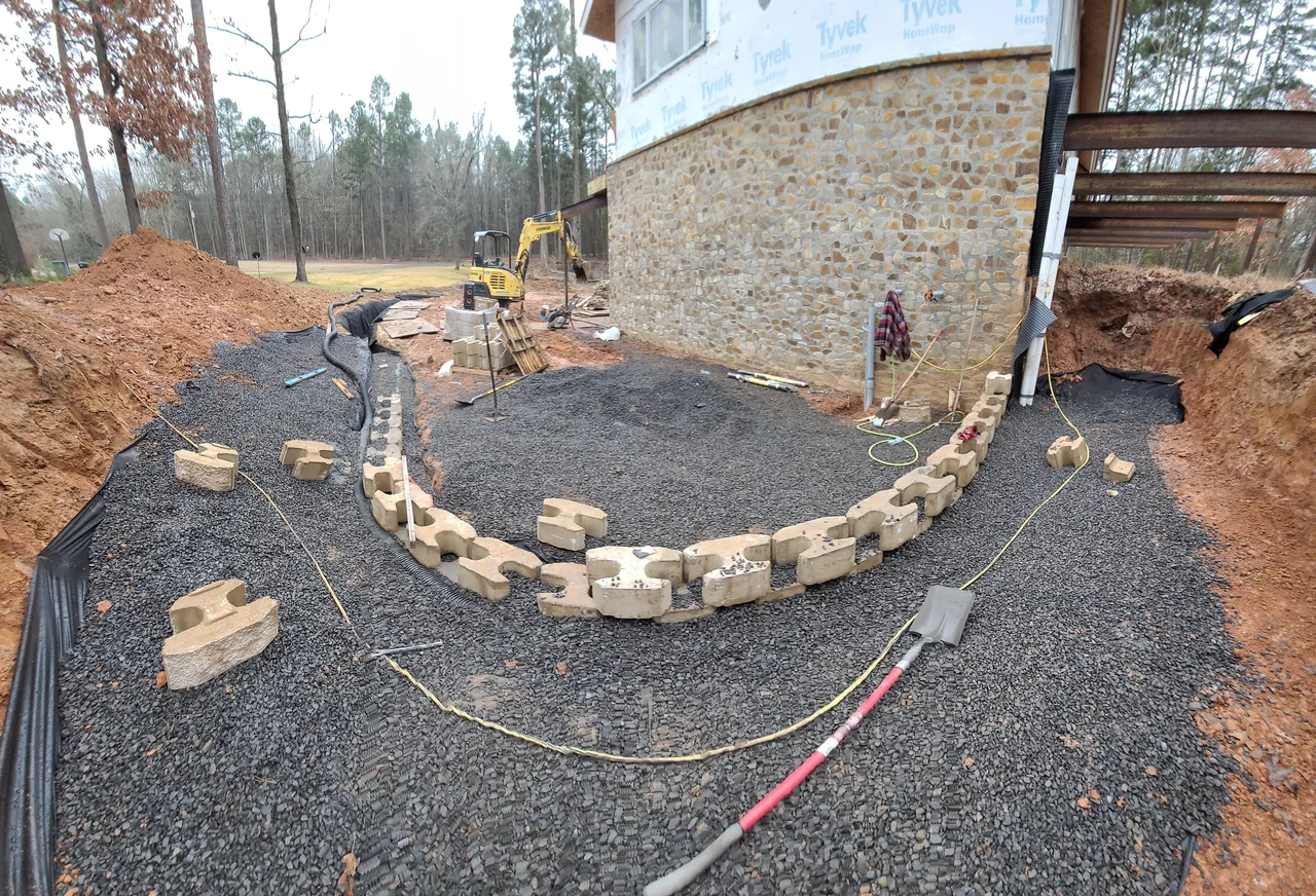 The first course of a curved retaining wall set out on gravel.