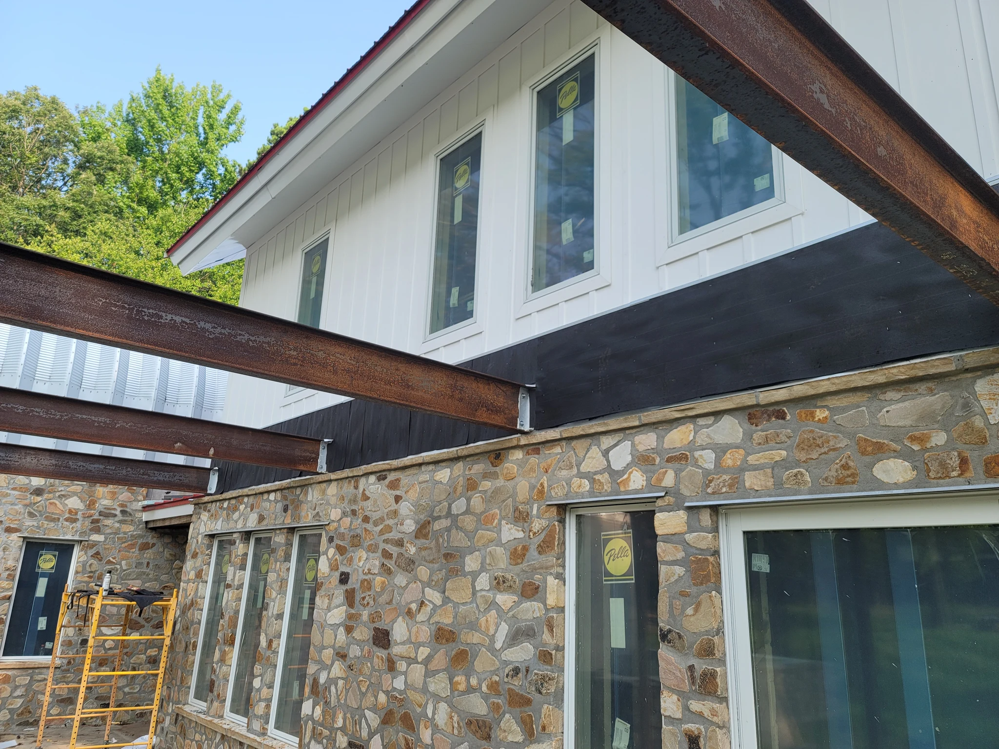 White board-and-batten siding above a stone base, with steel columns and glazing.