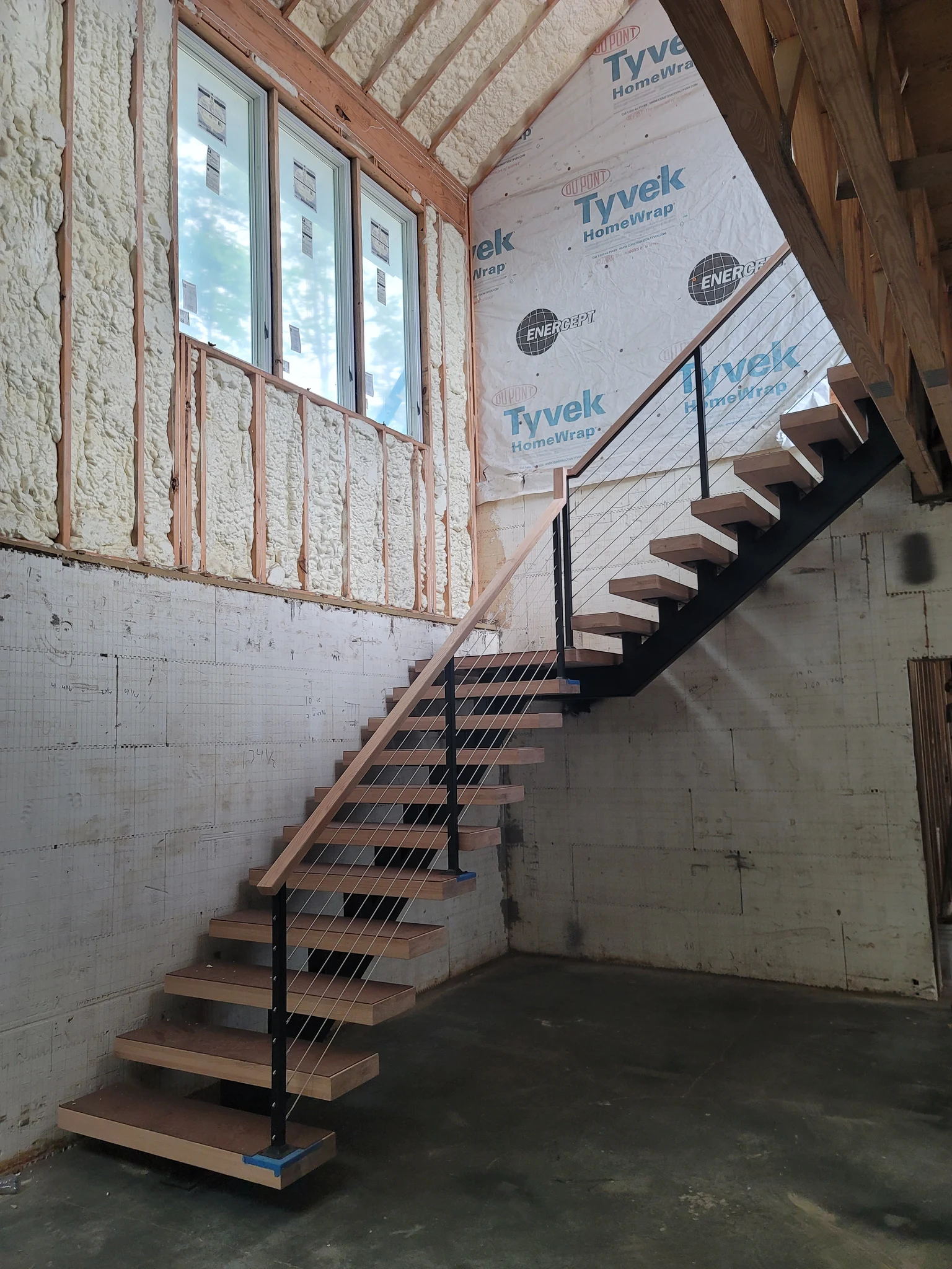 An open-riser stair with a steel stringer rising against a block wall.