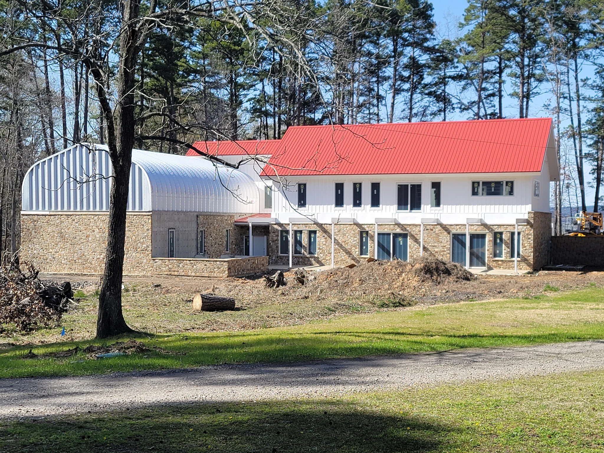 A custom home with stone veneer and standing-seam metal roofing seen across the lawn.