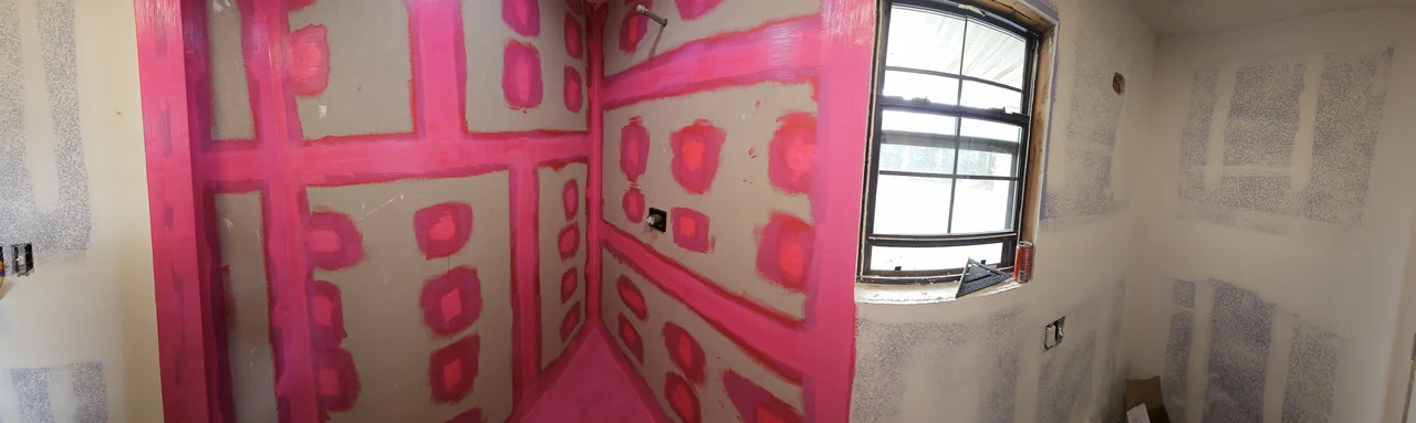 Wide view of the shower alcove with waterproofing membrane rolled over every seam, ready for tile.