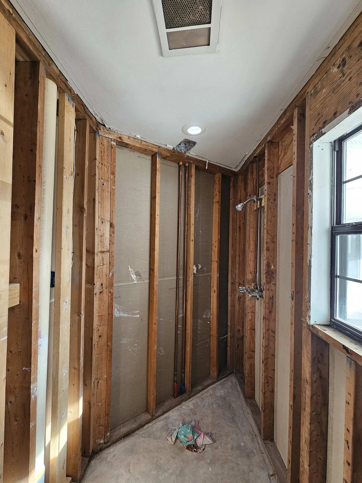 A bathroom stripped to framing with new copper shower valve piping roughed in.