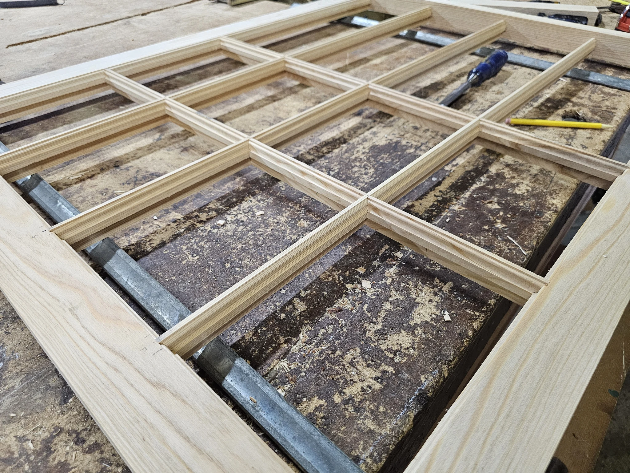 An assembled divided-light muntin grid laid flat on the shop bench.