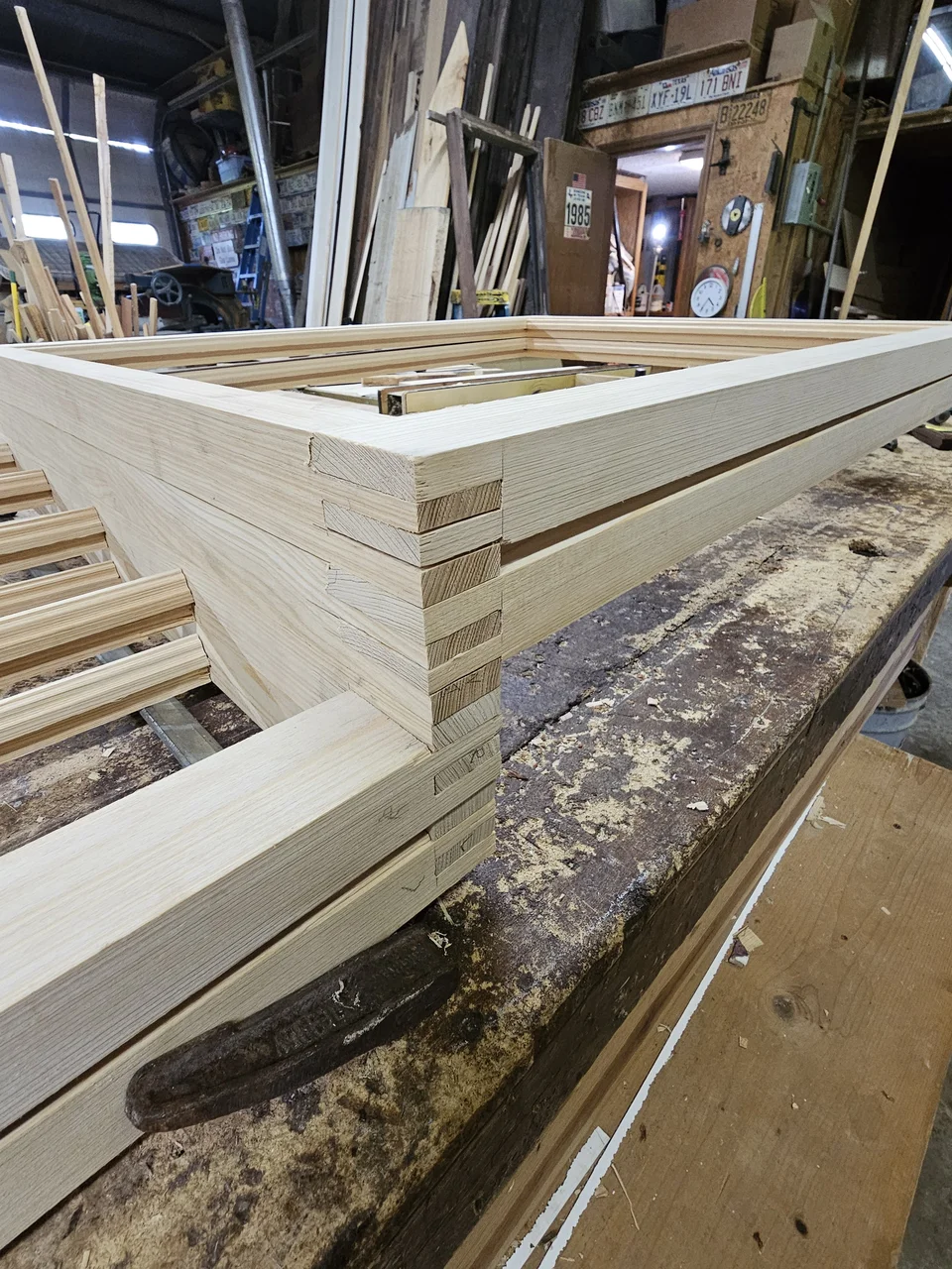 Close detail of a wedged mortise-and-tenon corner joint on a window frame.