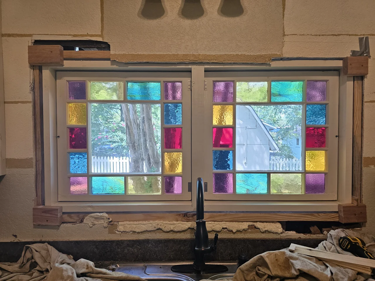 The finished leaded stained glass window installed above a kitchen sink, backlit.