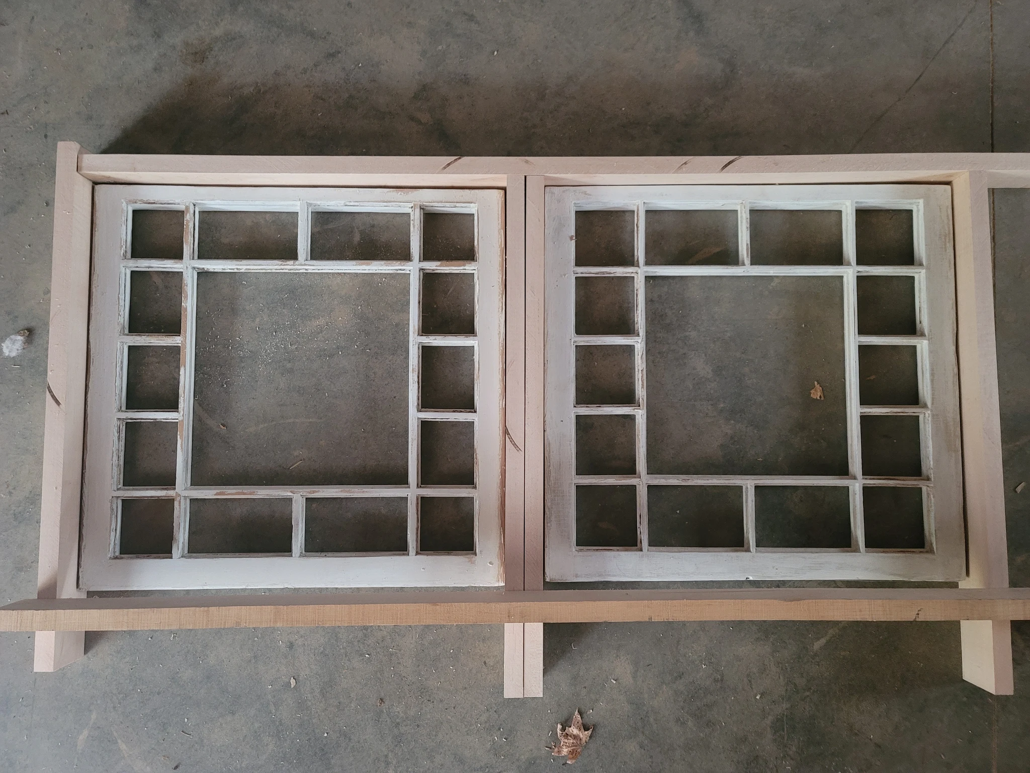 Two salvaged window sashes stripped and primed white, laid out on the shop floor.