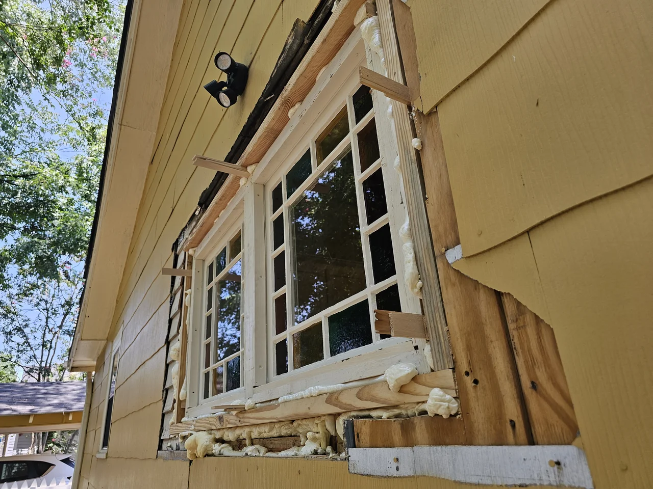 The wall opened and framed for the new window, siding cut back around it.