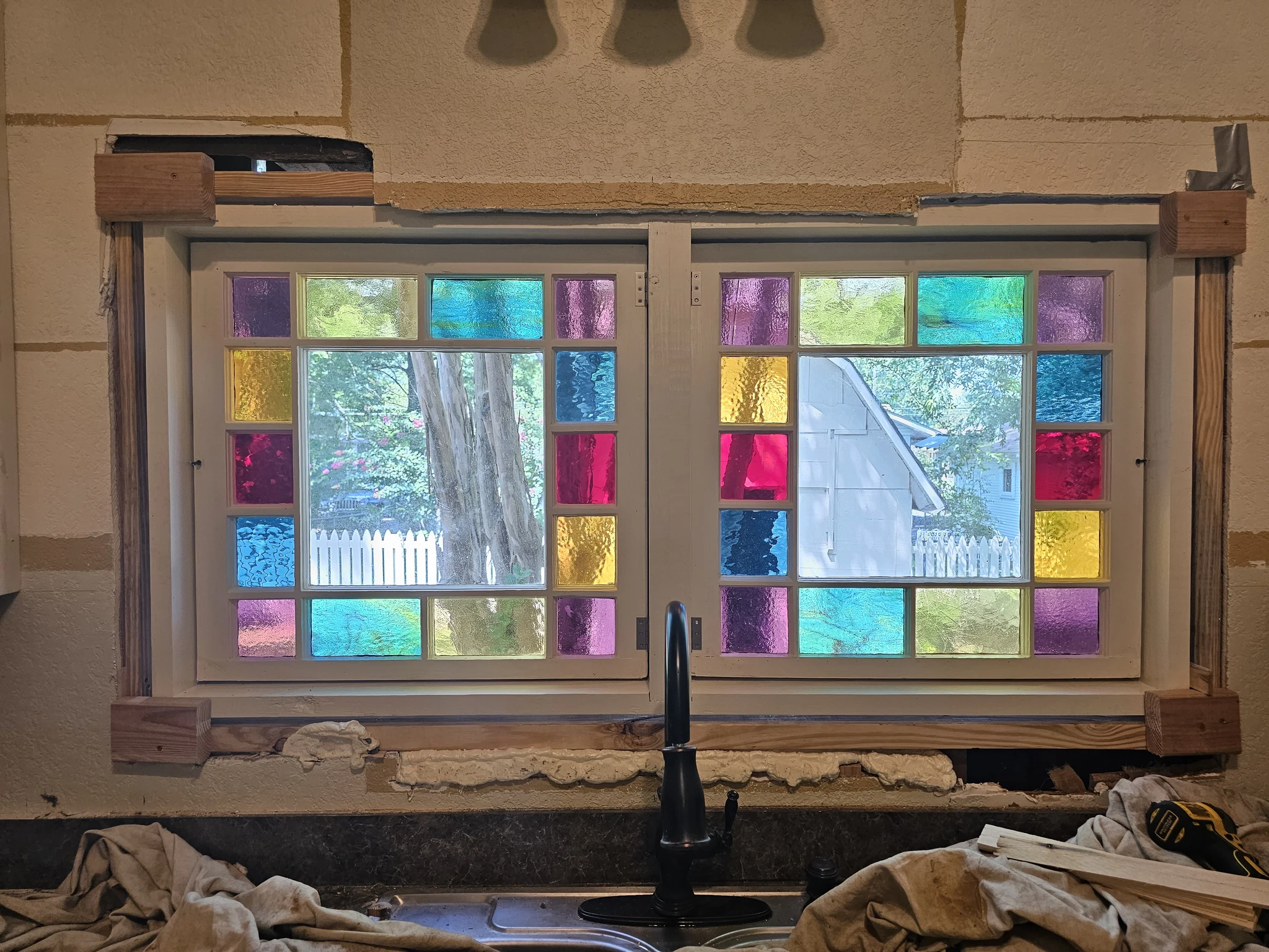 The finished leaded stained glass window installed above a kitchen sink, backlit.
