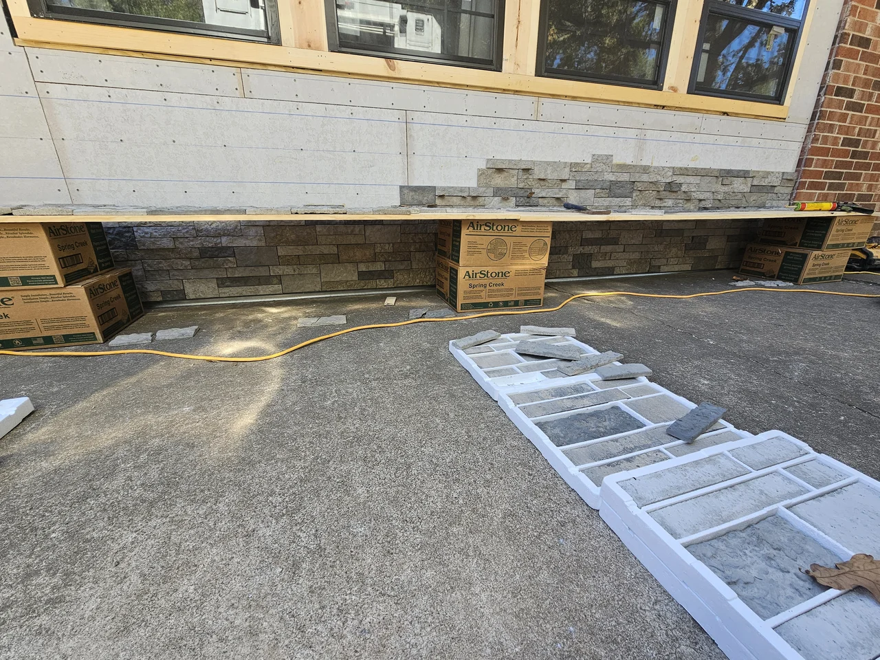 Stone veneer beginning at the base of a wall with stone staged on pallets.