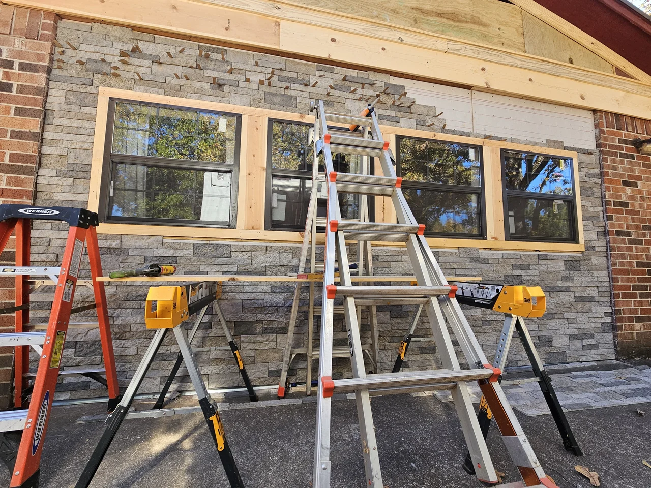 Ladders set in front of the nearly finished stone veneer wall.