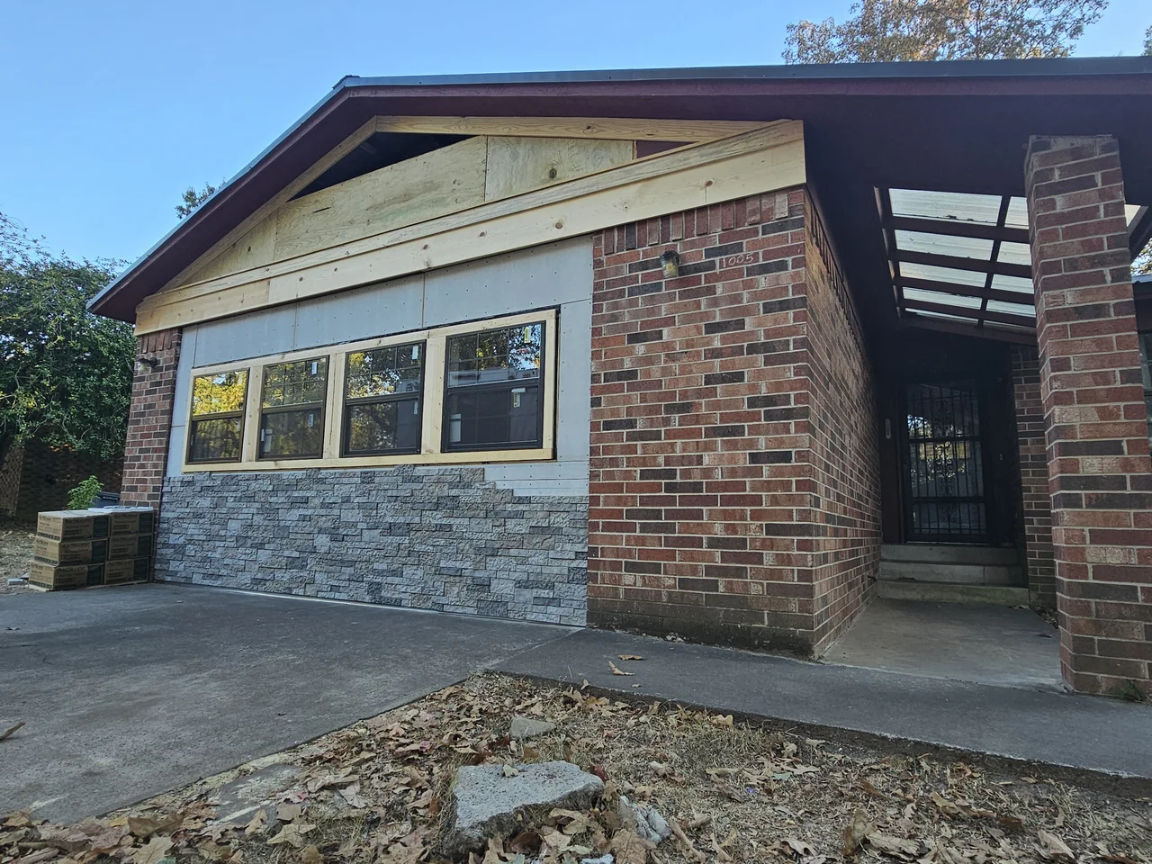 The gable end with stone veneer meeting brick and new windows installed.