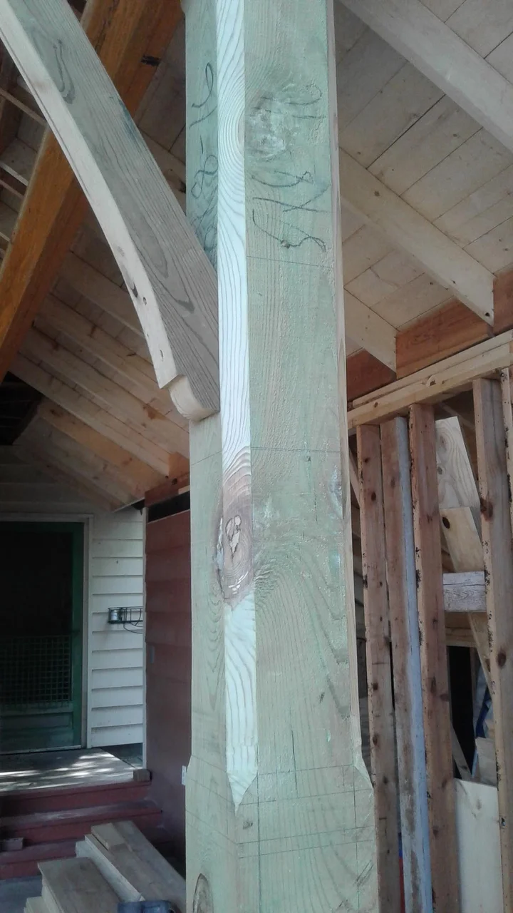 A timber post with a curved bracket during construction.