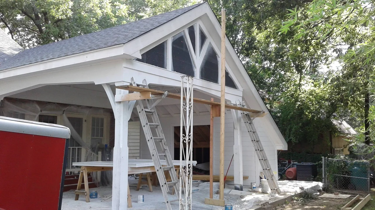 The carport frame standing with its timber trusses, ladders alongside.