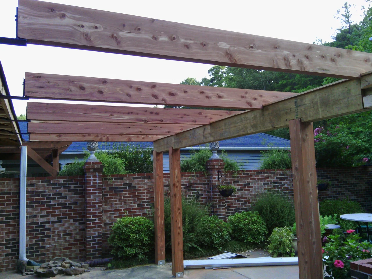 The pergola structure with rafters being installed across the beams.
